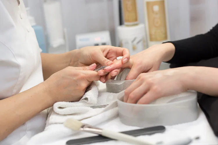 Nail Salon. Closeup Of Female Hand With Healthy Natural Nails Getting Nail Care Procedure.